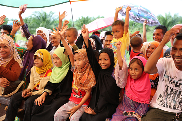 Children raise their hands in promise of coming to school every day